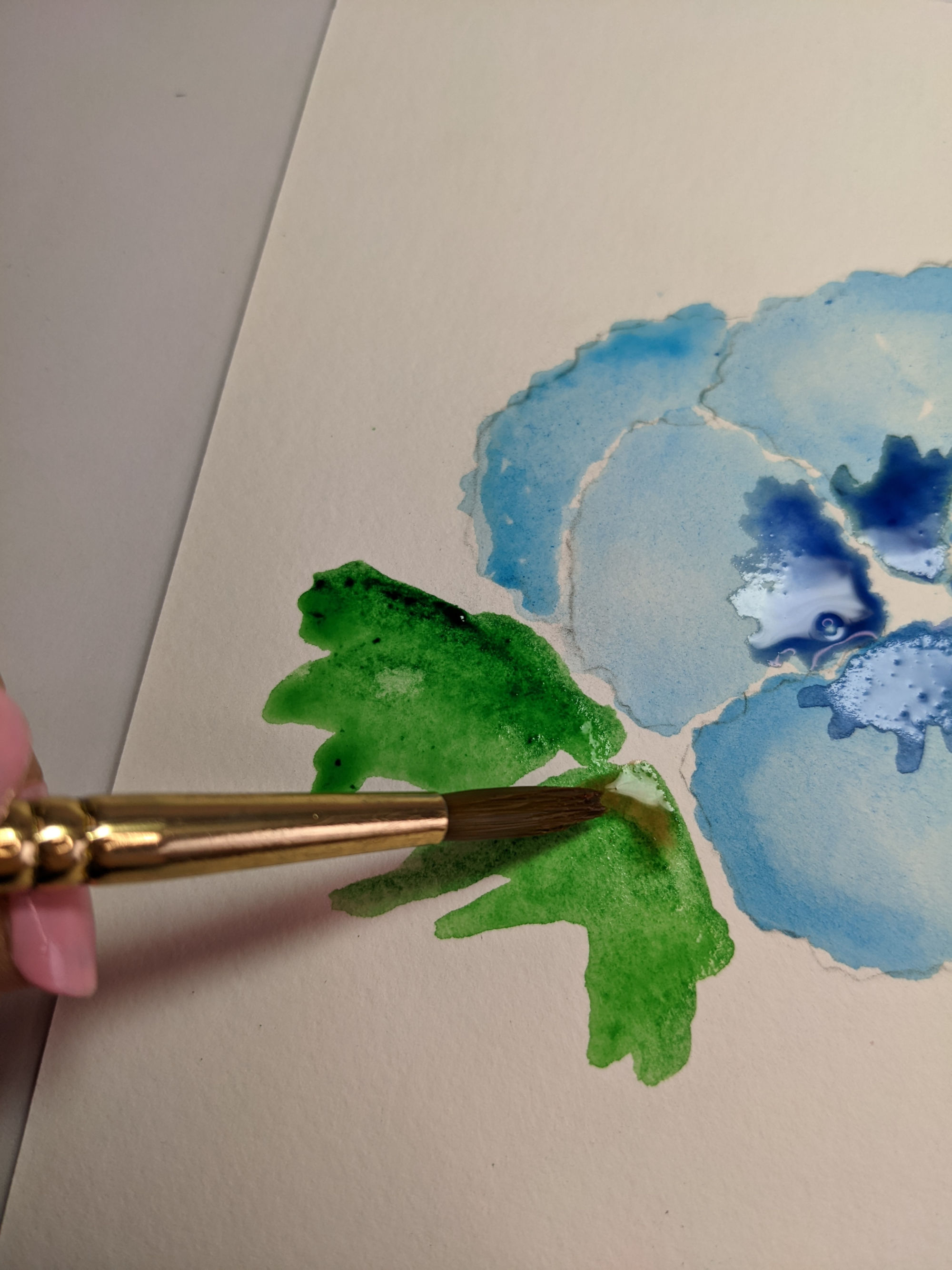 Adding green leaves to a watercolor flower